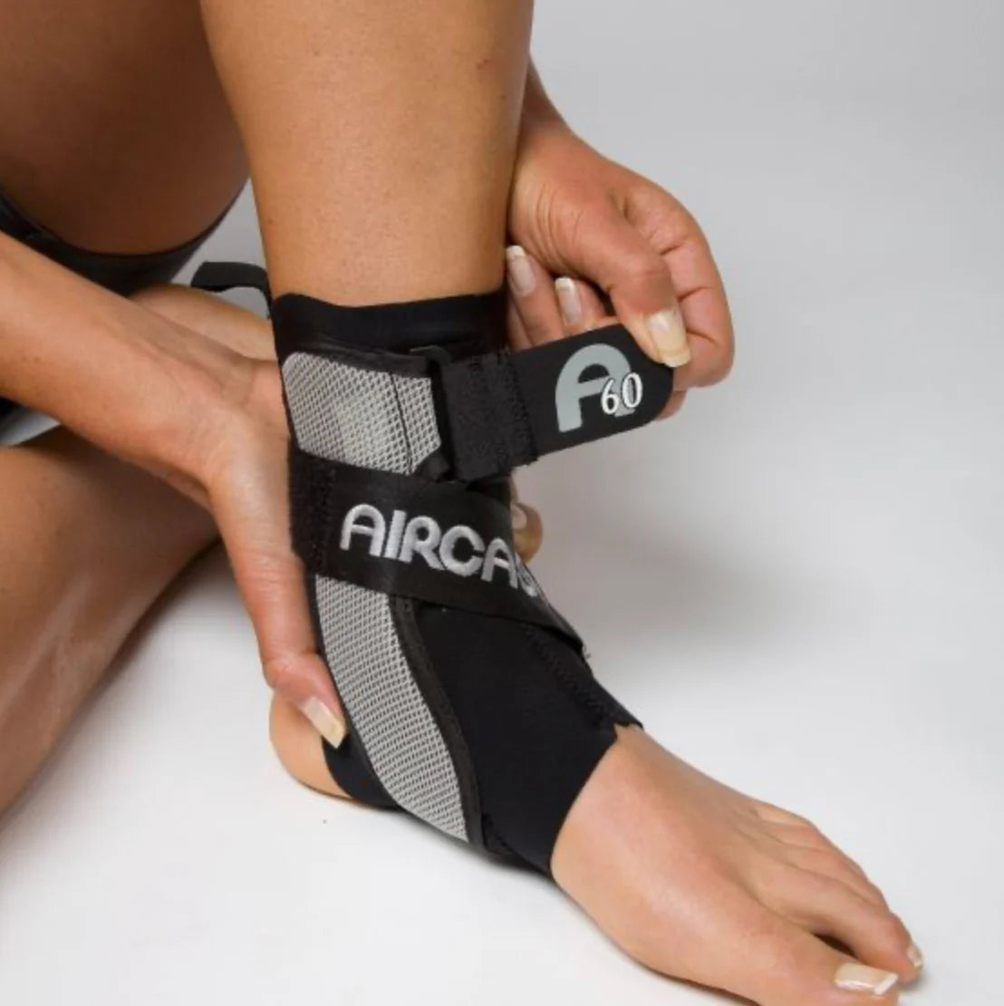 Person wearing an Aircast ankle brace on a plain background