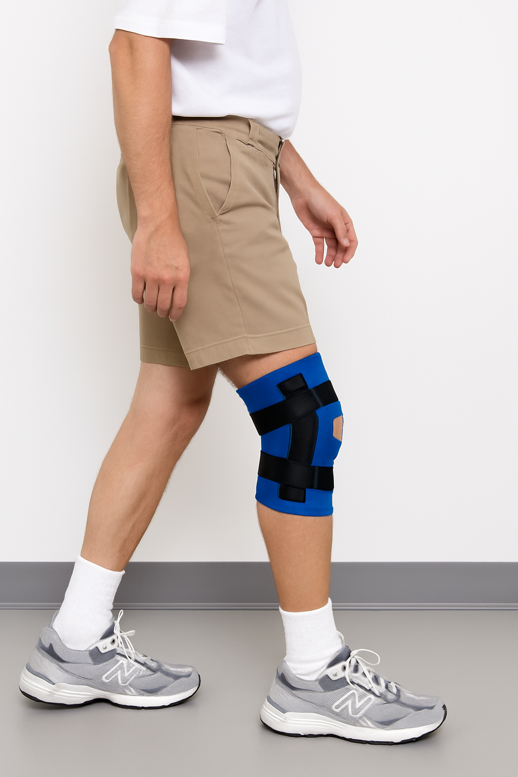 Person wearing a blue knee brace on one leg against a white background