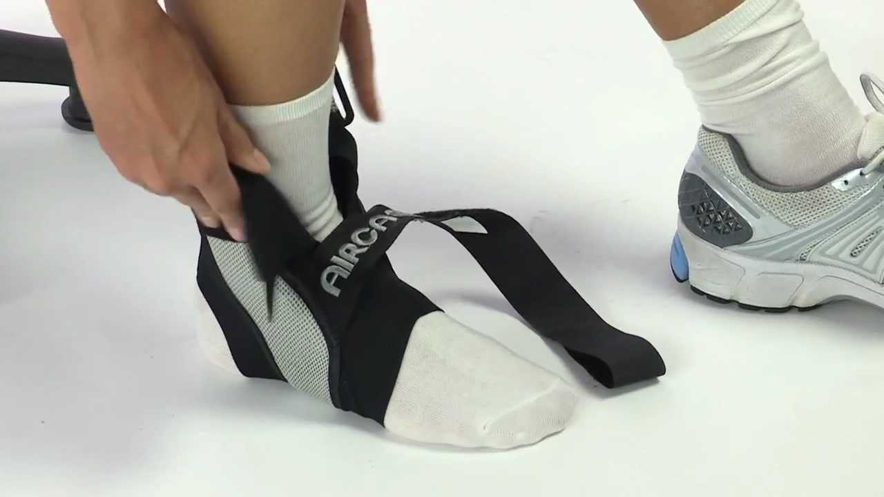 Person putting on a black ankle support brace with 'AIRCO' branding on a white background