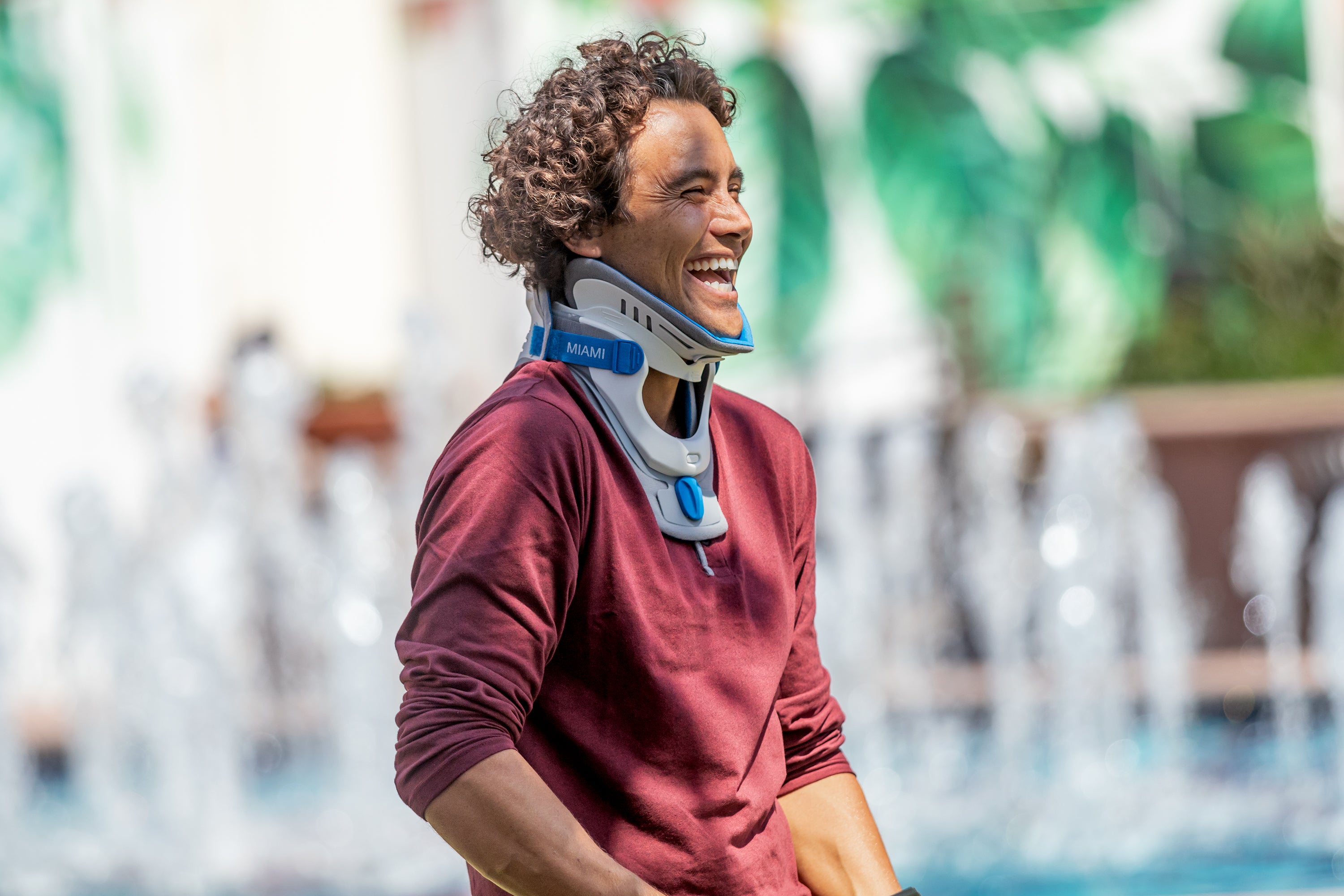 Person wearing a neck brace with a blurred fountain background